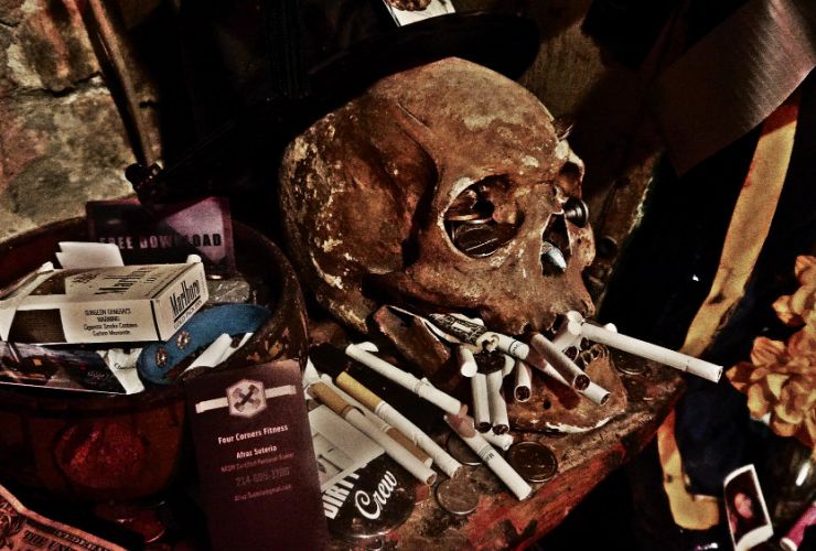 Cráneo humano con ofrendas y cigarrillos en el Historic Voodoo Museum de Nueva Orleans