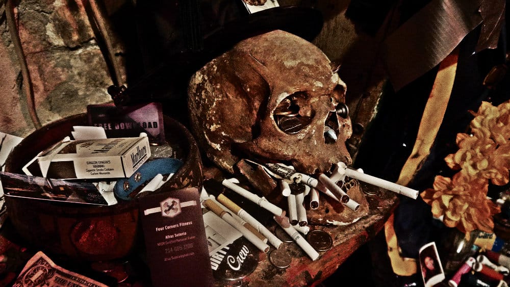 Cráneo humano con ofrendas y cigarrillos en el Historic Voodoo Museum de Nueva Orleans